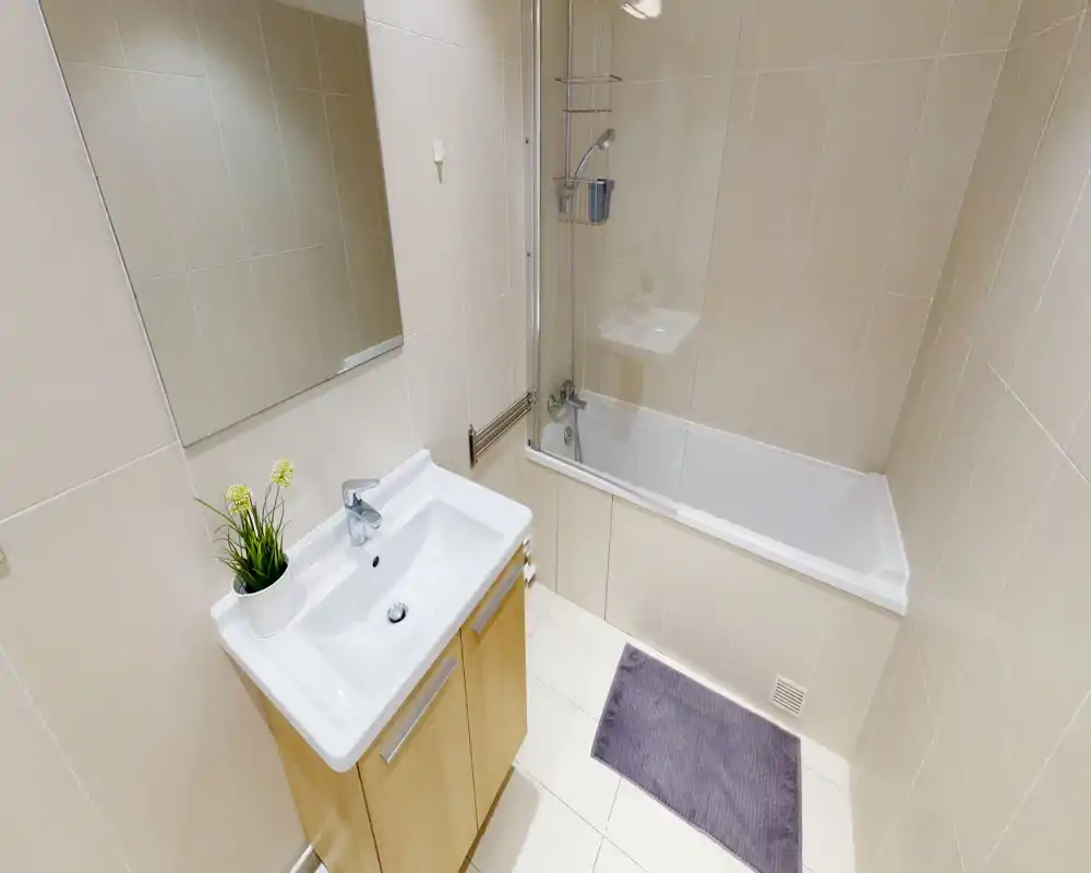 Salle de bain moderne et lumineuse avec baignoire et lavabo ; carrelage clair et miroir pour un rendu propre et minimaliste.