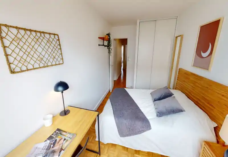 Chambre lumineuse et bien mise en scène avec une tête de lit en bois, literie blanche et coussins décoratifs — parfaite pour une personne ou un couple.