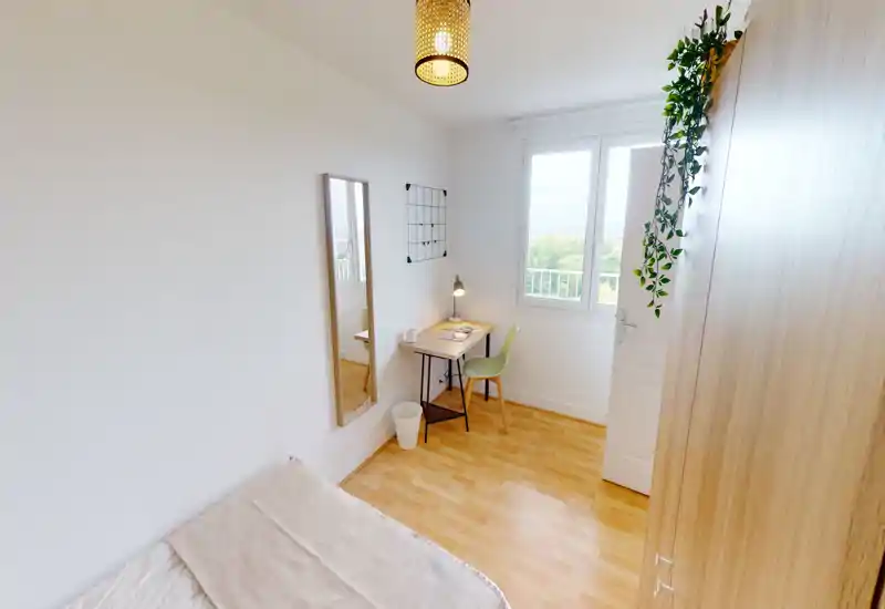 Chambre compacte et lumineuse avec un lit simple, un petit bureau près de la fenêtre et une belle lumière naturelle. Style minimaliste moderne, sol en bois et grand placard.