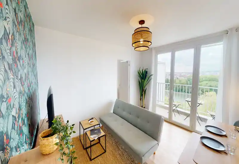 Salon lumineux et élégant avec un canapé compact, un papier peint décoratif et de grandes portes-fenêtres donnant sur un balcon avec vue — parfait pour se détendre et recevoir.