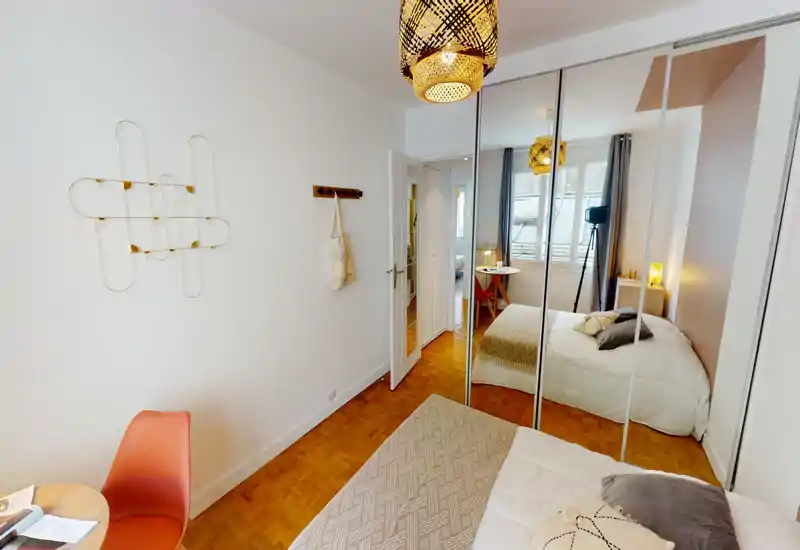 Bright, cozy bedroom with a double bed, mirrored wardrobe and warm decorative lighting; suitable for rental listings highlighting space and storage.