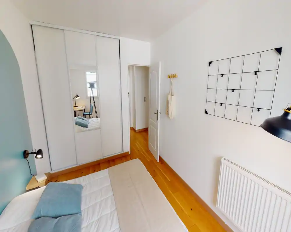 Camera da letto luminosa e moderna con letto matrimoniale in lino neutro, lampada a muro e armadio scorrevole con specchio, pavimento in legno caldo.