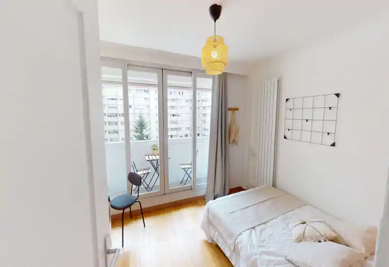 Bright, minimal bedroom with a comfortable single/double bed, soft linens and direct access to a small balcony — ideal for morning light and a calm stay.