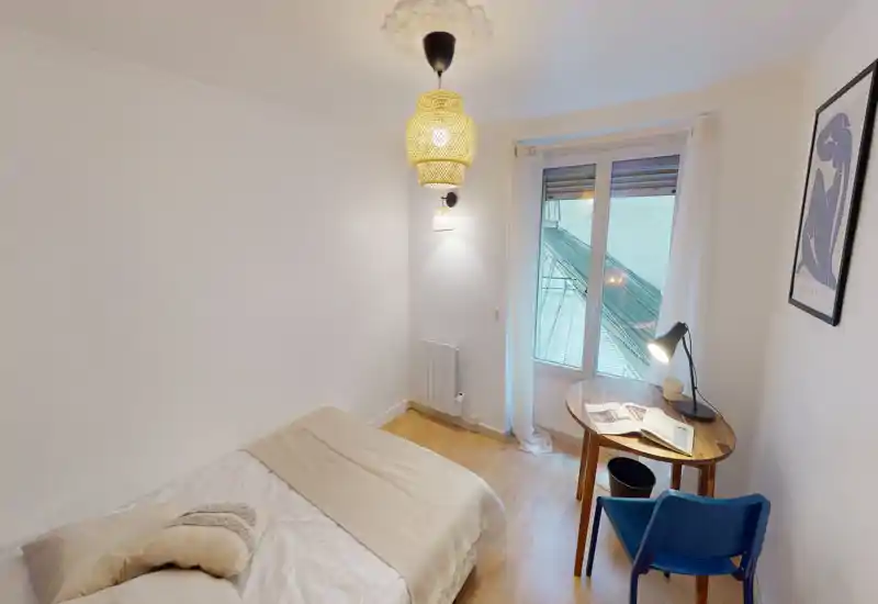 Bright, simply styled bedroom with a comfortable single/double bed, bedside lighting and a small desk by the window — ideal for a cozy solo stay or work-from-home nights.