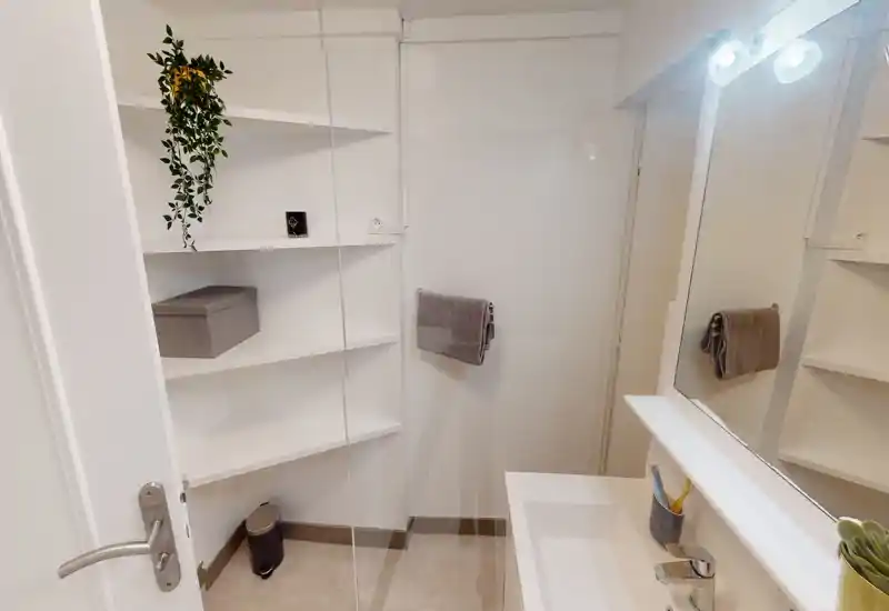 Compact, modern bathroom with white shelving, a sink and a mirror, bright lighting and neat finishing.