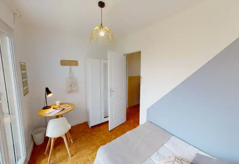 Bright, neatly staged bedroom with a single bed, soft textiles and a small work table by the window — ideal for a student or solo traveler.