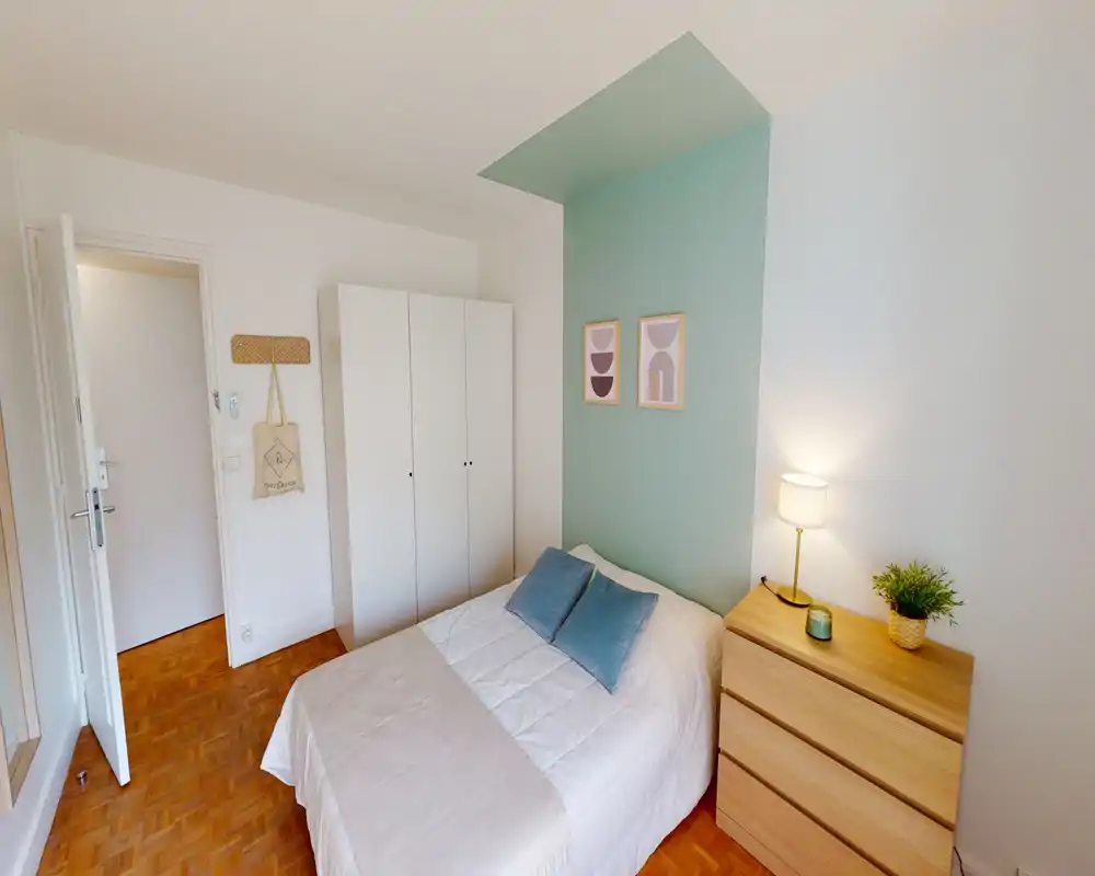 Camera da letto luminosa e ben arredata con letto matrimoniale centrale, parete d'accento verde acqua, comò in legno e armadio — accogliente e pronta per gli ospiti.