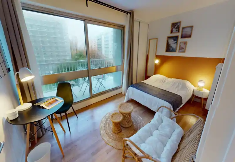 Bright, well-styled bedroom with a double bed, bedside tables and soft textiles; large sliding windows open to a small balcony letting in abundant natural light.