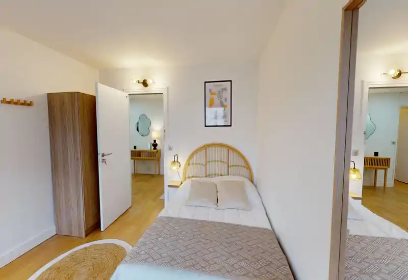 Bright, neatly styled single bedroom with a rattan headboard, cozy textiles and warm bedside lighting — ideal for a comfortable stay.