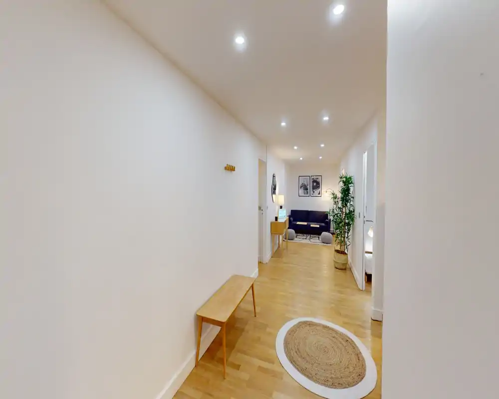 Bright, welcoming hallway with wooden flooring, a bench, decorative rug and a view into the living area; simple modern styling ideal for an entry photo.
