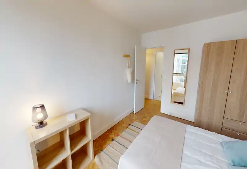 Camera da letto luminosa e ordinata con letto matrimoniale, armadio e mensola; tessuti morbidi e una lampada creano un’atmosfera accogliente.