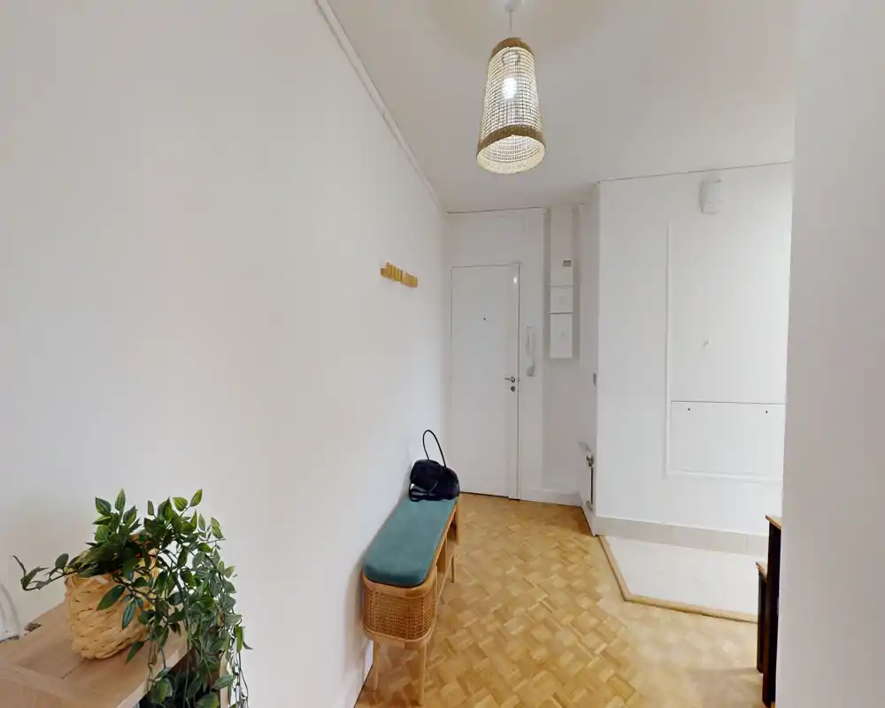 Bright entry hallway with a bench, pendant light and parquet flooring — tidy, well-lit space ideal for welcoming guests.