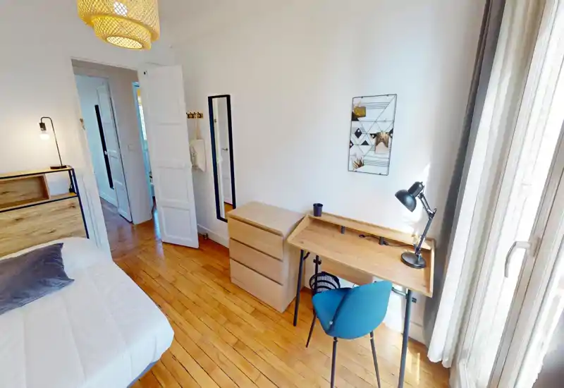 Camera da letto luminosa e accogliente con testiera in legno, letto comodo e scrivania vicino alla finestra — perfetta per riposo e lavoro da remoto.