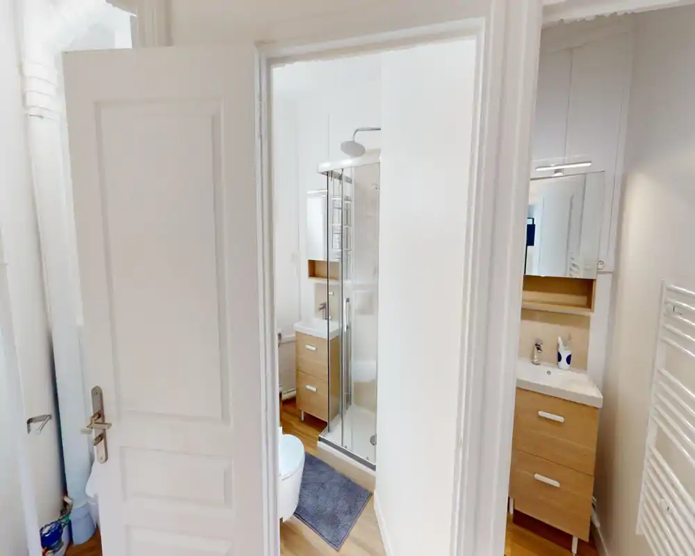 Bagno moderno e luminoso con box doccia angolare in vetro, mobile lavabo con cassetti effetto legno, specchio e scaldasalviette.