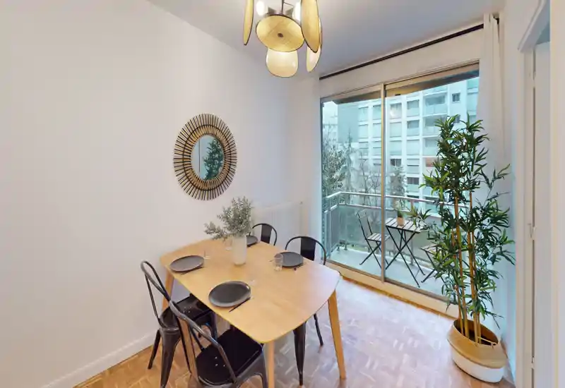 Zona pranzo luminosa e arredata con un tavolo in legno per quattro persone, sedie in metallo e porta scorrevole che si apre su un piccolo balcone — perfetta per pranzi indoor/outdoor.