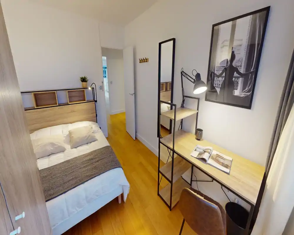 Camera da letto accogliente e luminosa con letto matrimoniale comodo, mensole sullo schienale e scrivania in legno con lampada — ideale per riposo o smart working.