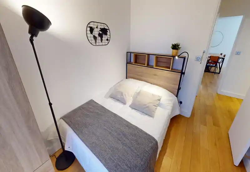 Chambre compacte et bien mise en scène avec un lit double, du linge de lit doux et une tête de lit en bois dotée d'étagères; parquet chaud et palette apaisante pour une atmosphère accueillante.