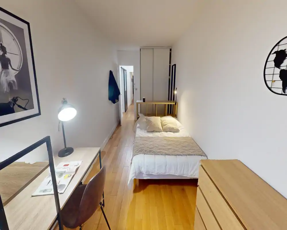 Camera da letto moderna e luminosa con un comodo letto matrimoniale, lampade da comodino e una cassettiera in legno; una scrivania vicino alla finestra rende la stanza funzionale per lavoro e relax.