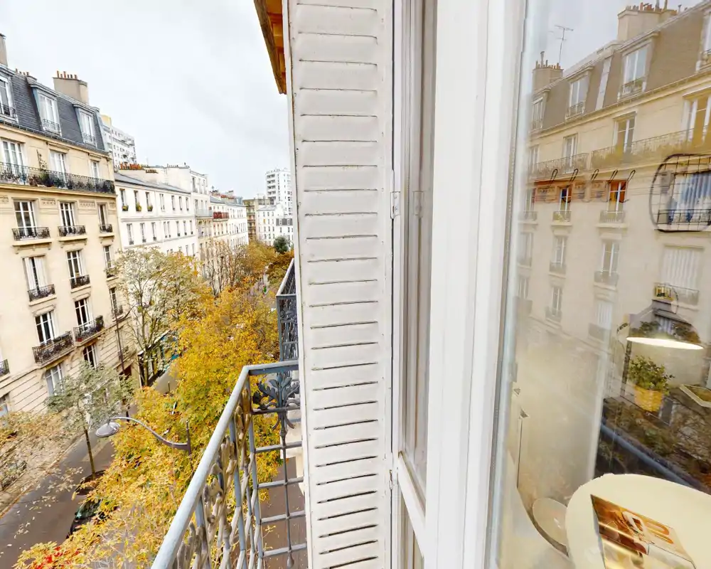 Balcone in stile parigino con vista su una strada alberata e facciate classiche — perfetto per gustare il caffè del mattino e ammirare la città.