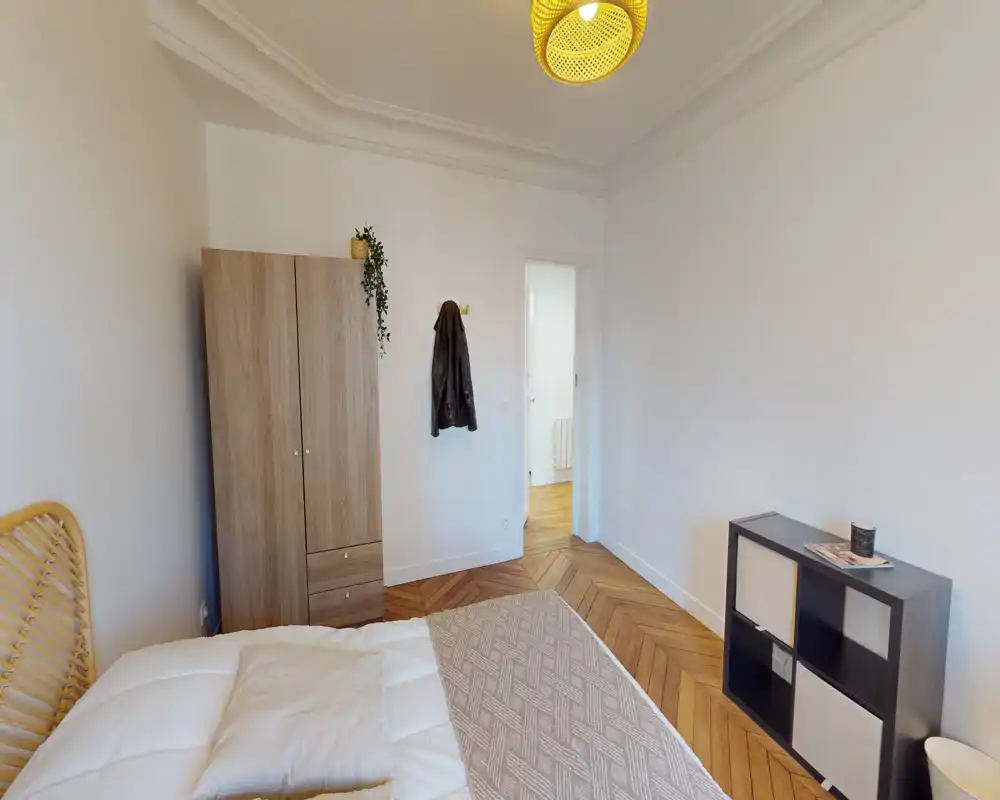 Camera da letto luminosa e accogliente con letto matrimoniale, pavimento in parquet e armadio. L'ambiente è caratterizzato da luce calda e arredi semplici.