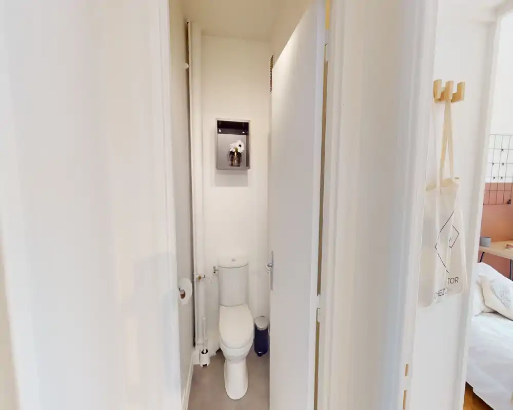 Compact, well-lit WC with a modern toilet, narrow layout and a decorative recessed shelf above the cistern.