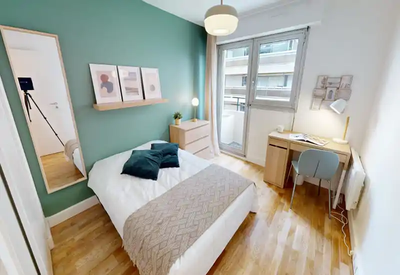 Bright, styled bedroom with a comfortable double bed, decorative cushions and a small desk by the window — ideal for work and rest.
