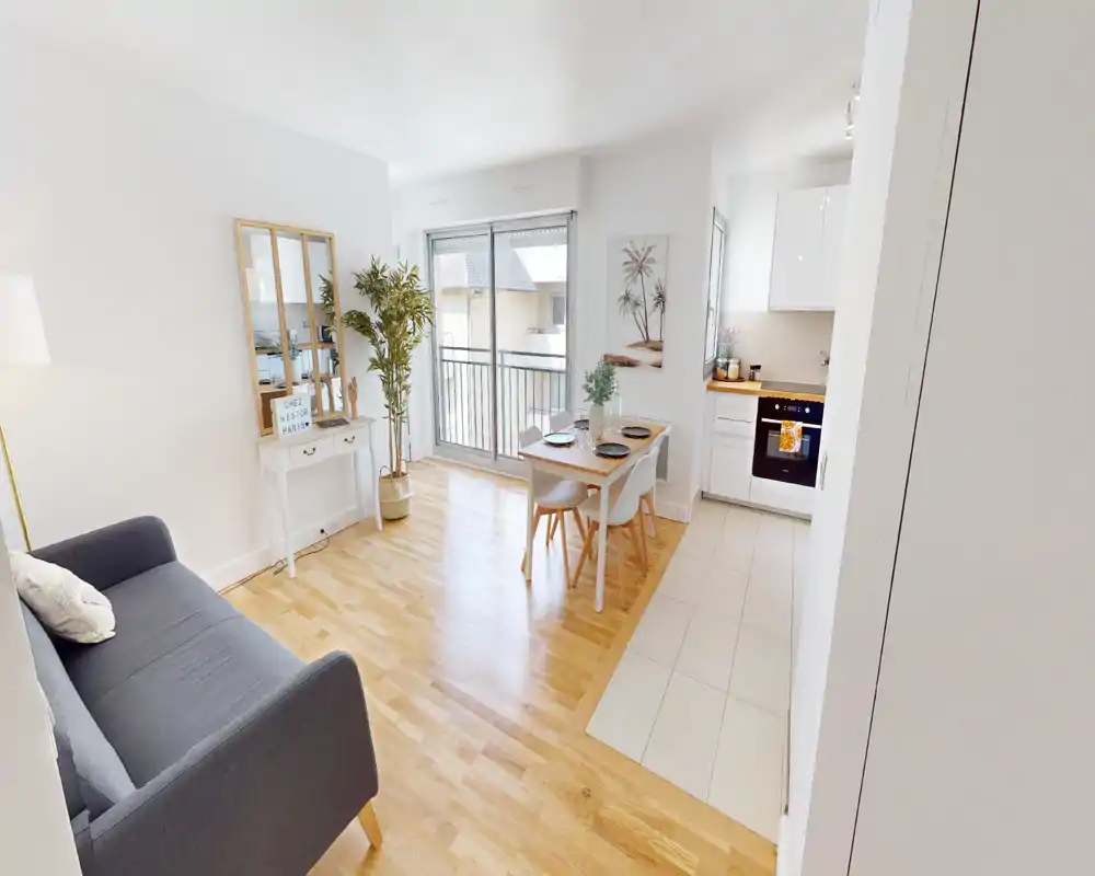 Bright, modern open living area with a compact dining table, comfortable sofa and natural light from sliding doors — ideal for a small apartment.