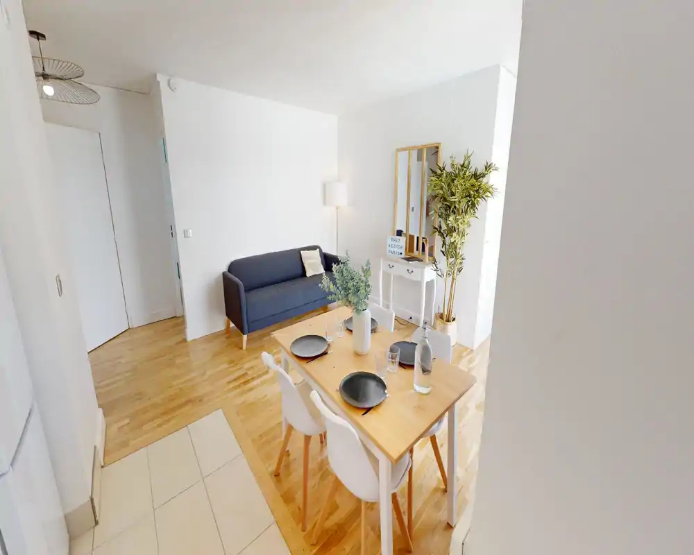 Bright, modern living and dining area with a compact sofa, wooden dining table set for four, and decorative plants creating a cosy, well-styled space.
