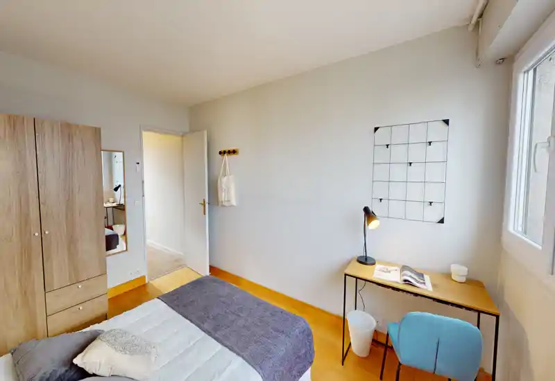 Camera luminosa e ordinata con letto matrimoniale, armadio in legno e una piccola scrivania vicino alla finestra — perfetta per riposo e smart working.