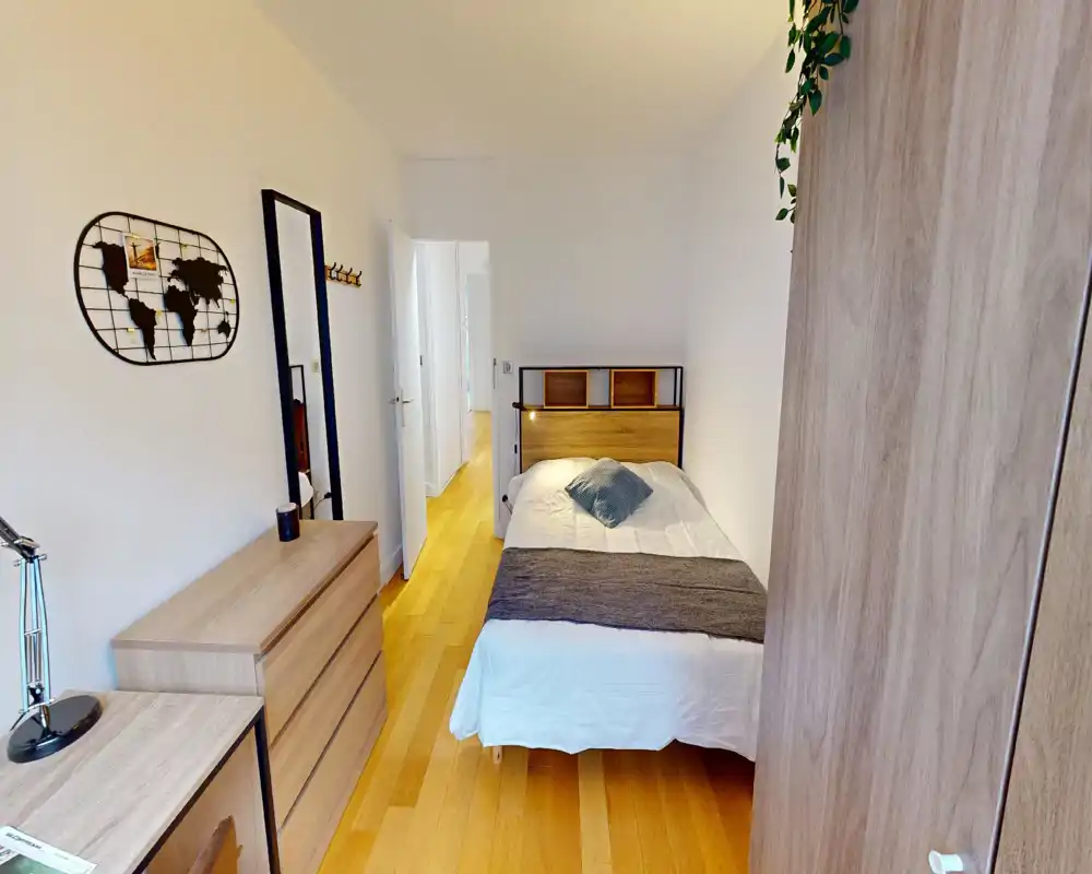 Dormitorio moderno y luminoso con cama doble, cabecero de madera y muebles a juego. Suelo de parquet cálido y decoración sencilla y acogedora, ideal para una estancia cómoda.