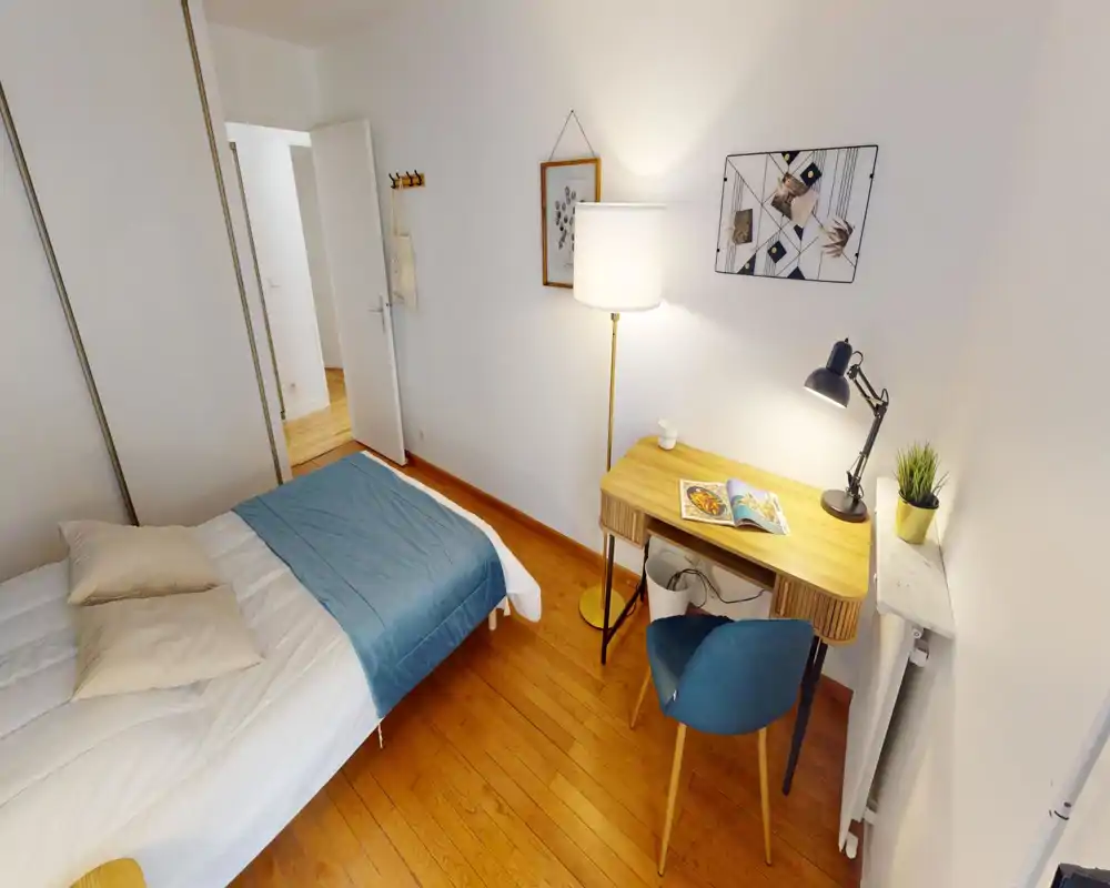 Bright, tidy bedroom with a double bed, bedside textiles and a wooden desk with a reading lamp — ideal for comfortable short or long stays.