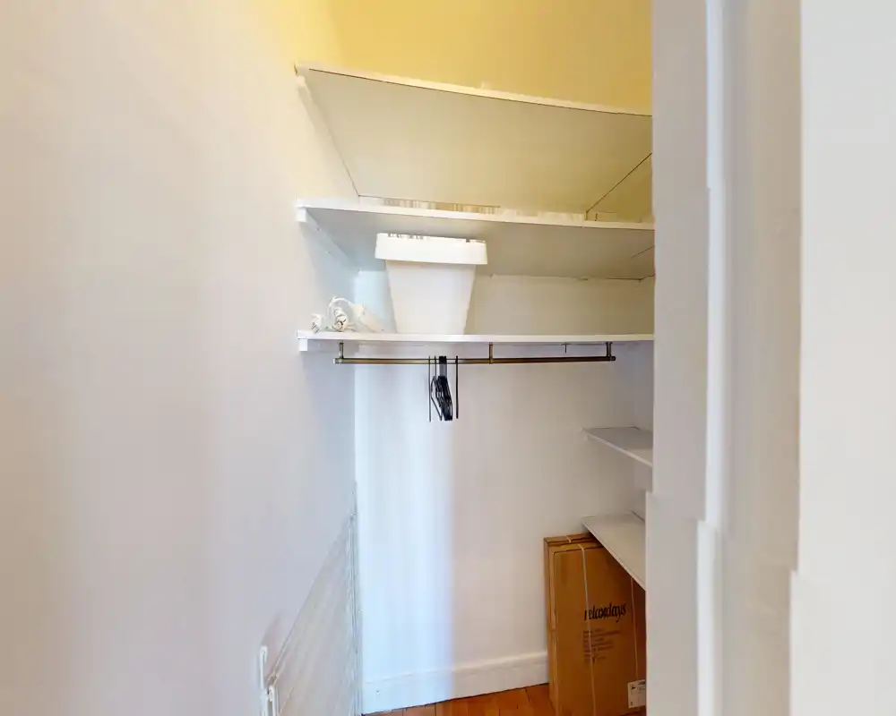 Petit placard/réserve avec étagères, tringle pour vêtements et quelques objets rangés — pratique pour le rangement ou comme dressing.