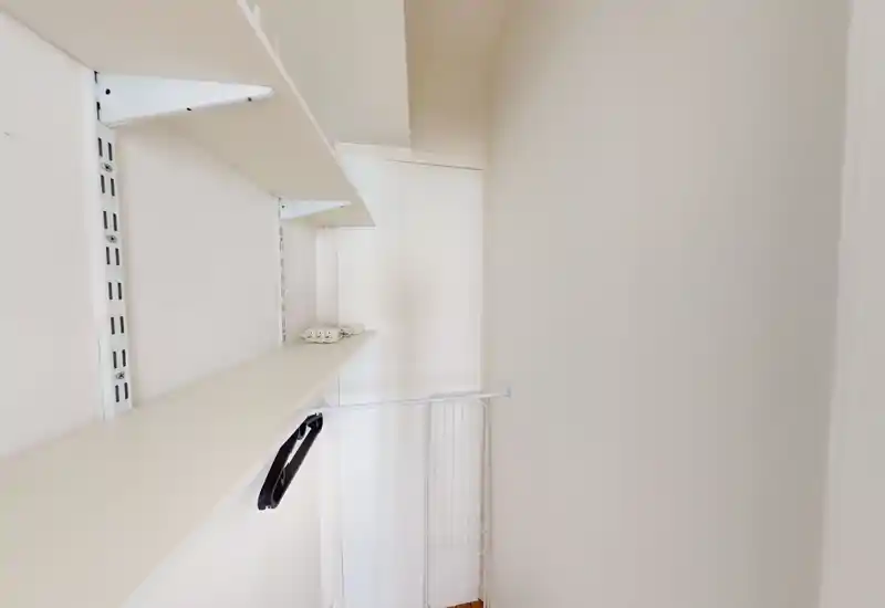 Small narrow storage/wardrobe niche with built-in shelves and a single hanging rail; appears to be a closet or utility alcove rather than a full room.