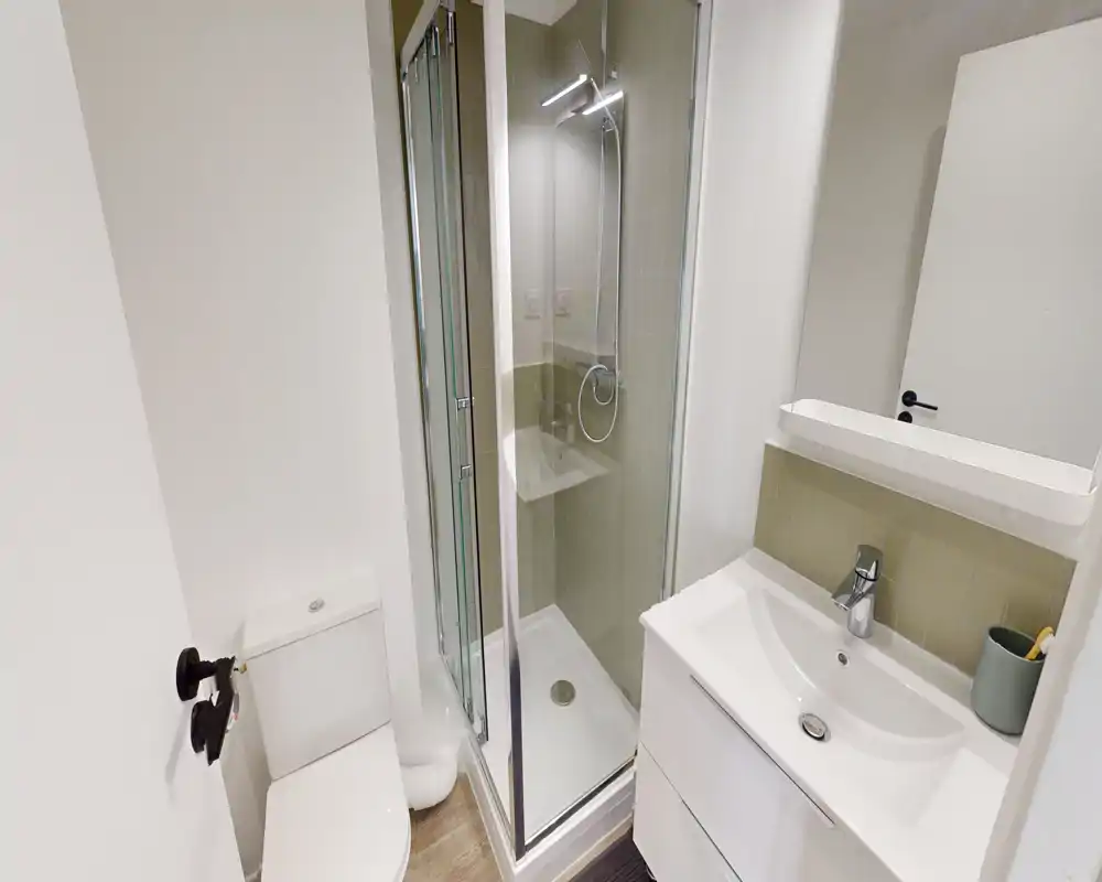 Bagno moderno e compatto con doccia con box in vetro, WC e mobile lavabo — pulito, luminoso e progettato efficacemente per uno spazio ridotto.