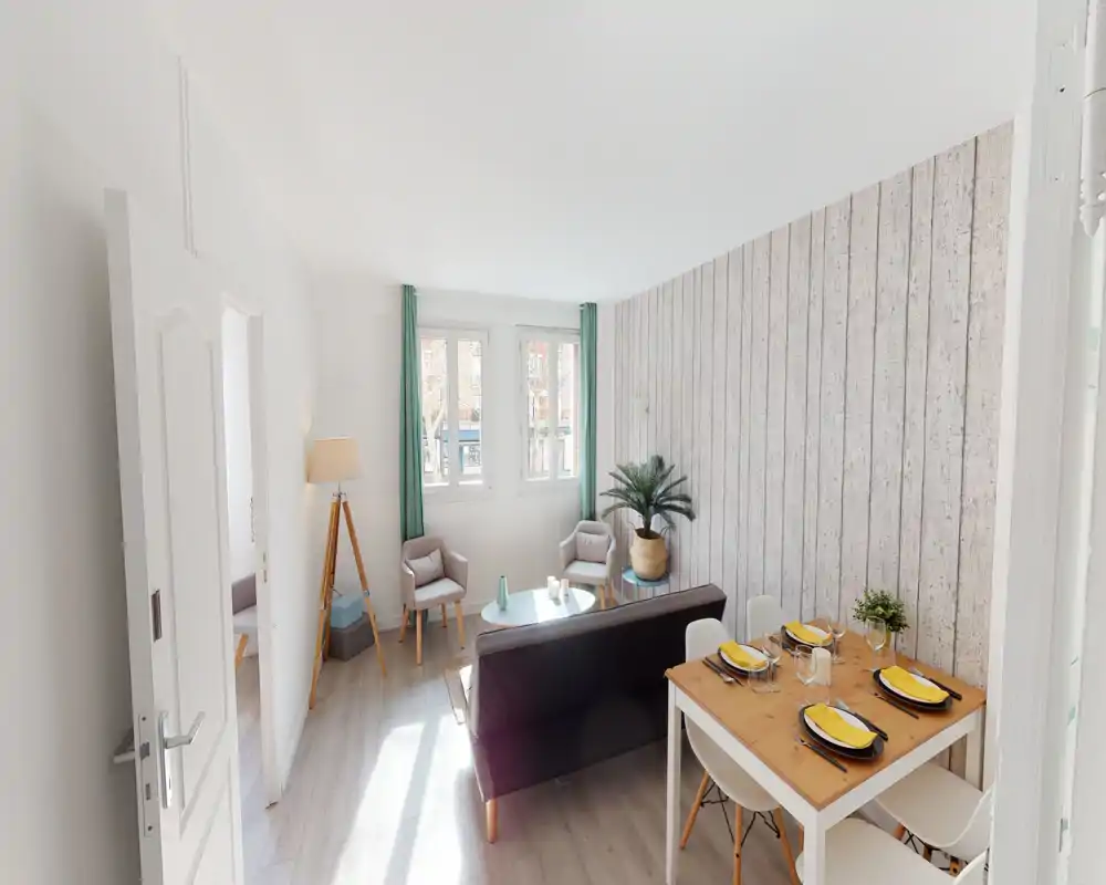 Soggiorno luminoso e moderno con area conversazione compatta, tavolino e piccolo tavolo da pranzo per quattro; parete effetto legno e piante donano calore contemporaneo.