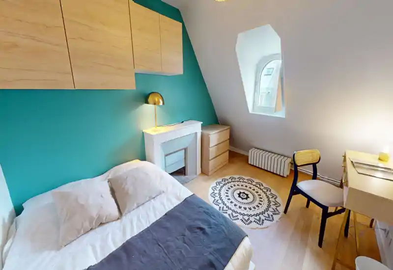 Chambre lumineuse et soignée avec lit double, mur d'accent turquoise, rangements en bois et petit bureau — idéale pour un séjour confortable.