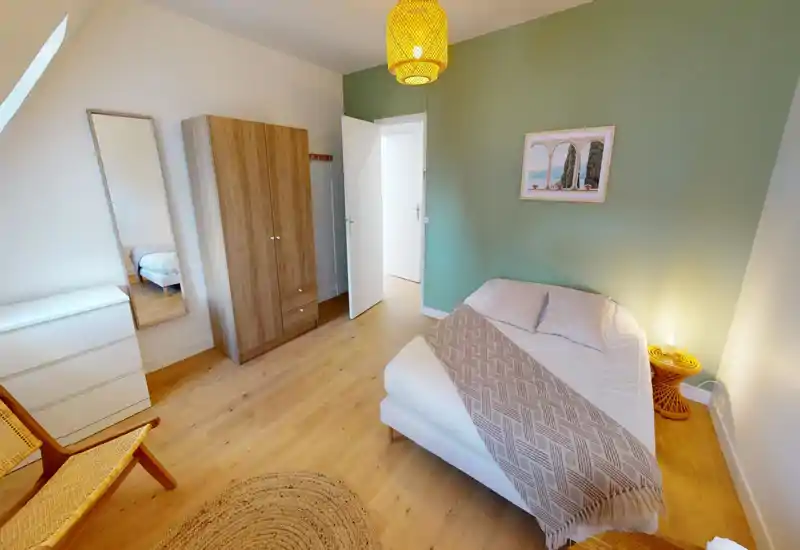 Bright, cozy bedroom with a double bed, soft textiles and warm lighting. Natural wood floors, a wardrobe and a full-length mirror complete the room for comfortable stays.