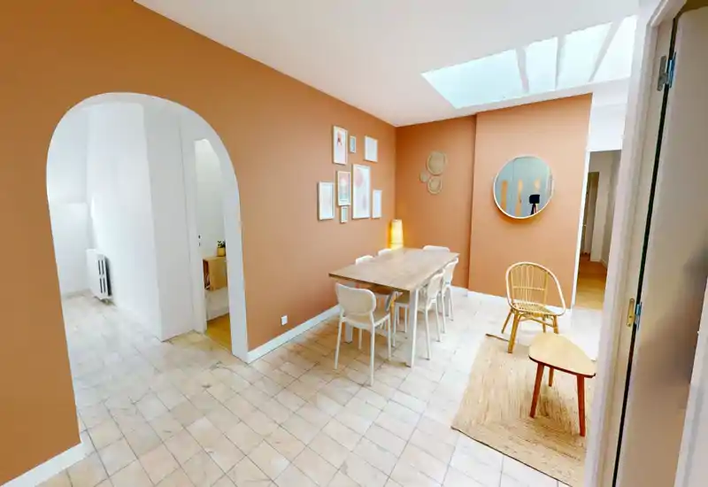 Warm, styled dining room with a wooden table, six chairs, decorative wall art and a skylight providing soft natural light — ideal for listing photos.