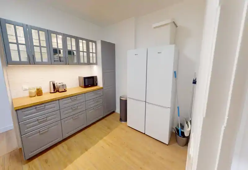 Modern kitchen with grey cabinetry, wooden countertops and two white refrigerators; well-lit and neatly organized with small appliances on the counter.