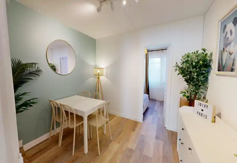 Cozy dining nook with a small white table for four, soft wall color, decorative mirror and floor lamp; stylish, well-staged space ideal for compact apartment listings.