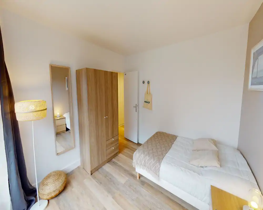 Chambre simple lumineuse et bien aménagée avec lit confortable, armoire en bois et éclairage chaleureux — parfaite pour un étudiant ou un invité seul.