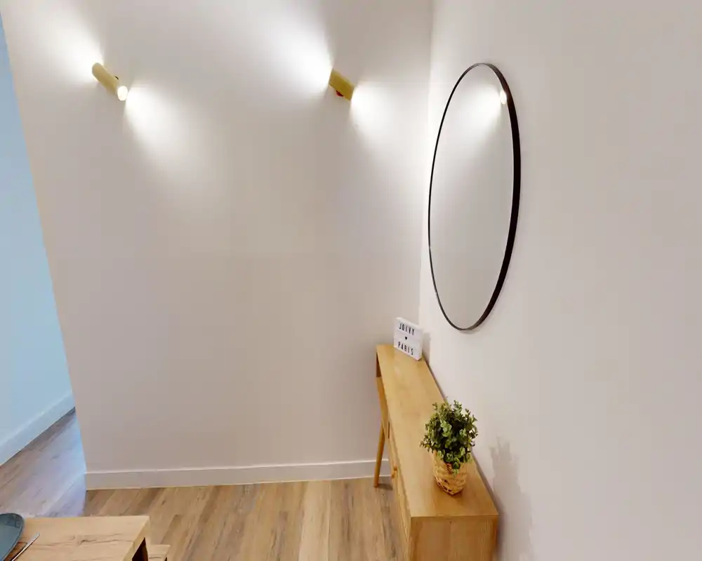 Entrée moderne et lumineuse avec console en bois, miroir rond mural et éclairages muraux chaleureux — style minimaliste et accueillant pour un hall d'entrée.