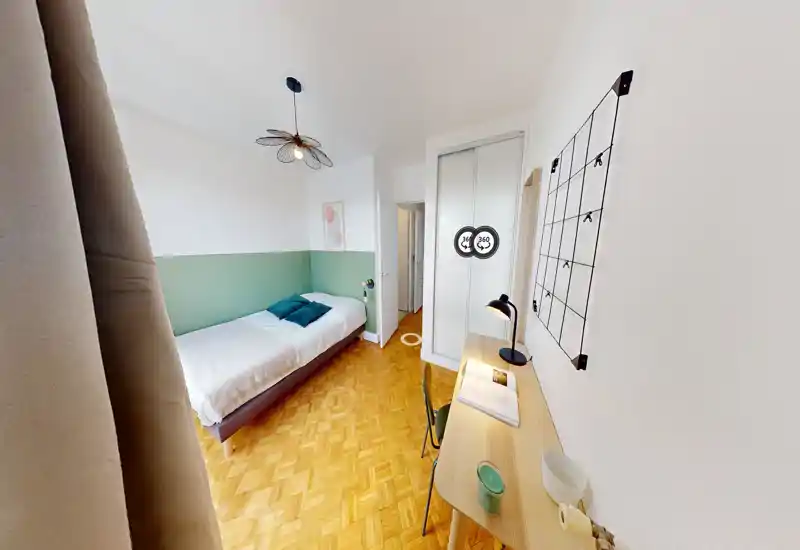 Bright, well-staged single bedroom with a comfortable bed, green accent wall and a tidy desk — ideal for a student or solo traveler.