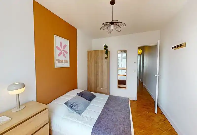 Camera da letto luminosa e accogliente con letto matrimoniale, armadio in legno e parete d'accento calda; biancheria fresca e cuscini creano un ambiente ideale per affitti brevi.
