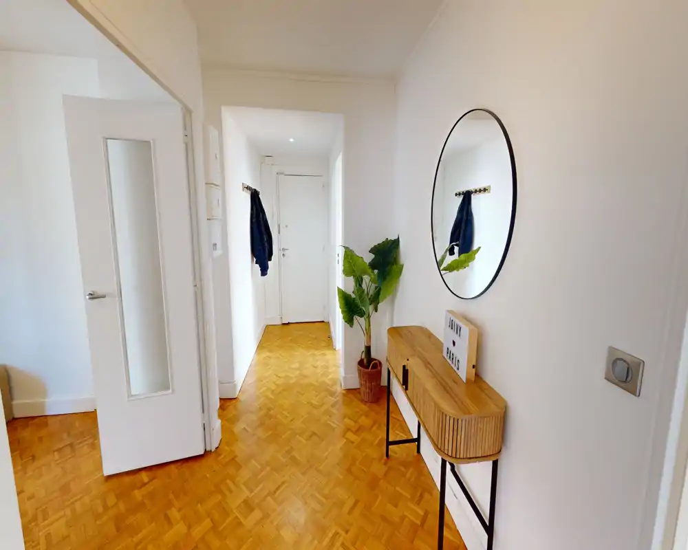 Bright, welcoming entrance hallway with parquet flooring, a decorative console table, round wall mirror and coat hooks near the front door.