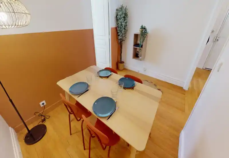 Coin repas lumineux et aménagé avec une table en bois pour quatre, mur bicolore chaud et plantes décoratives pour une ambiance cosy.