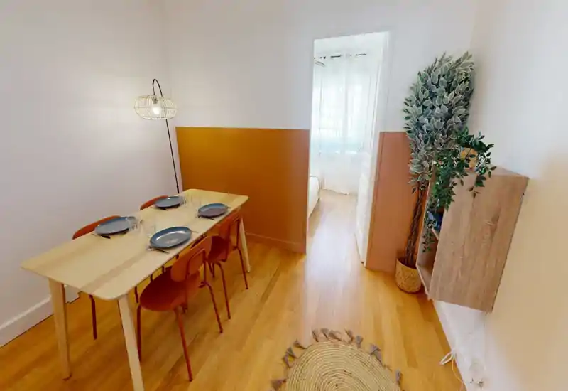 Salle à manger lumineuse et aménagée avec une table en bois pour quatre personnes, accents terracotta et parquet naturel — chaleureuse et moderne.