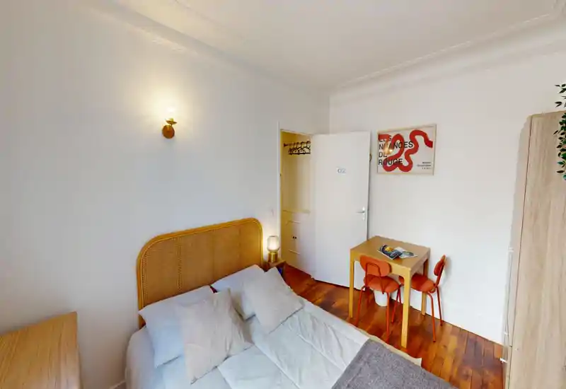 Chambre lumineuse et bien décorée avec une tête de lit en rotin, lit double confortable, lampes de chevet et petit bureau contre le mur — idéale pour un séjour cocooning.