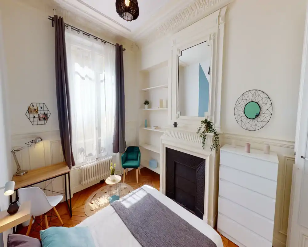 Camera da letto luminosa e di stile con ampia finestra, camino decorativo e letto ben rifatto. Tessuti morbidi, una poltrona accogliente e scaffali curati creano un’atmosfera invitante, perfetta per un annuncio.