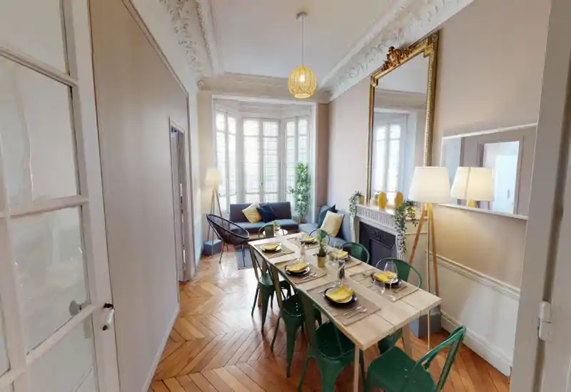Grande salle à manger élégante avec une longue table pour six, de grandes fenêtres en baie et des détails décoratifs raffinés qui créent une ambiance chaleureuse et accueillante.